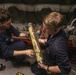 Sailors perform maintenance on a jack water pump