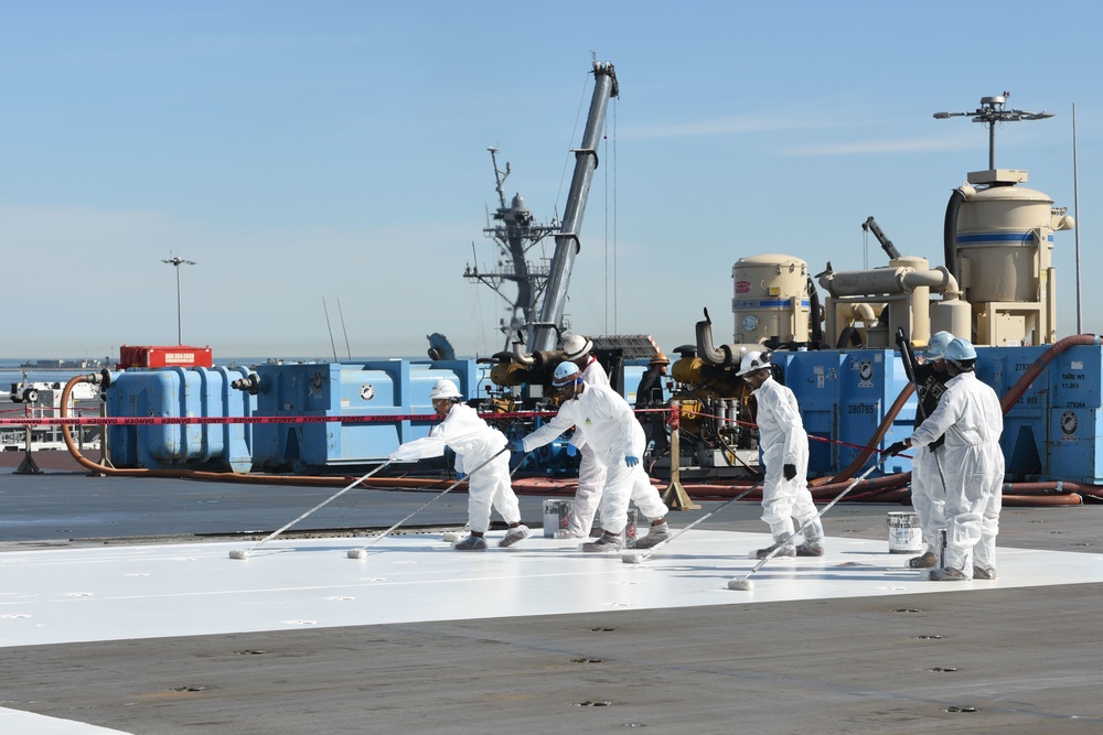 U.S. Navy civilian personnel paint the flight deck
