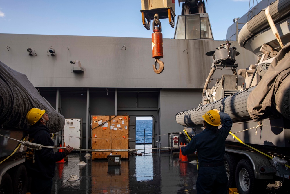 Sailors watch a crane move.