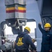 Sailor directs crane operato while Sailor waits to attach a insulated hook