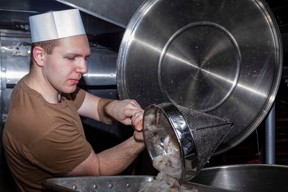 Sailor pours shrimp into a pan