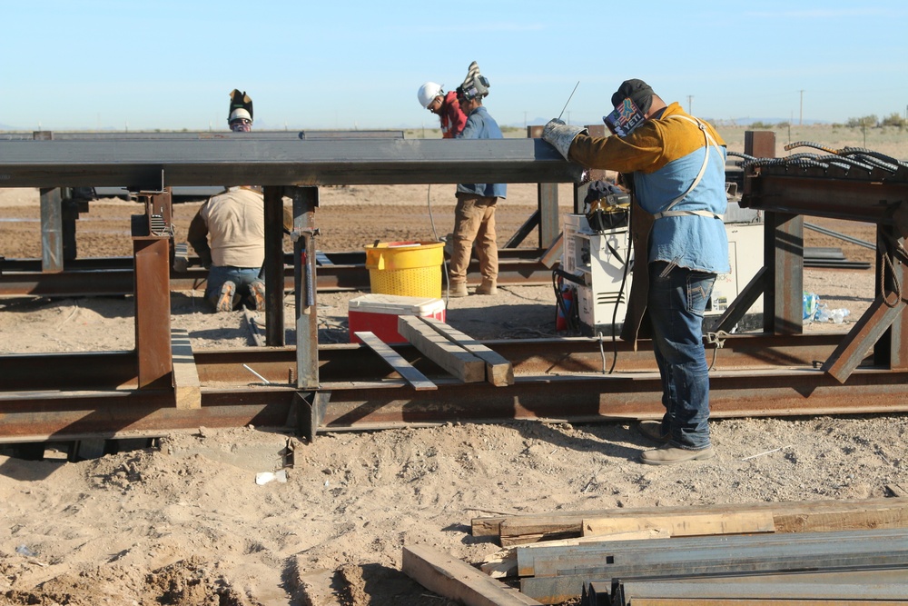 Workers construct border barrier panels