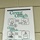 A public health poster titled 'Cover Your Cough' is displayed on a beige/cream cinder block wall. The poster provides illustrated instructions on preventing the spread of germs through proper coughing, sneezing, and hand hygiene etiquette. It is issued by the CDC, Minnesota Department of Health (MDH), and APK, with a '2020' date visible on a partially visible document below.