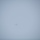 A single aircraft is visible in an overcast, hazy sky, appearing as a small silhouette near the center of the frame. The image is dominated by a uniform grey-blue sky with very low contrast and heavy atmospheric haze. The aircraft is barely distinguishable from the background due to the foggy or cloudy conditions.