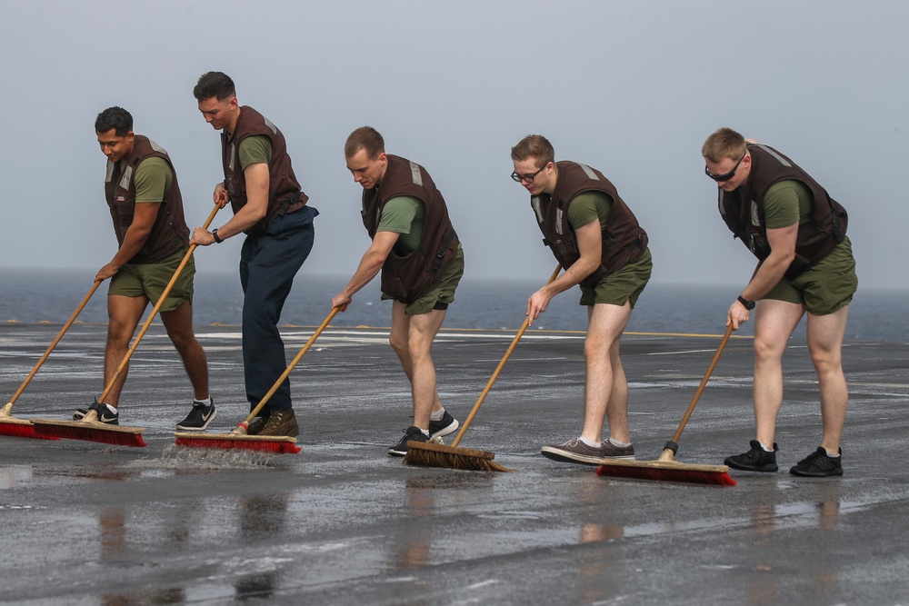 Marines and Sailors aboard the Bataan scrub the flight deck