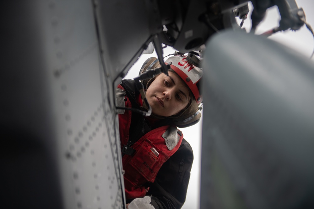 U.S. Sailor performs maintenance on an MH-60S Sea Hawk