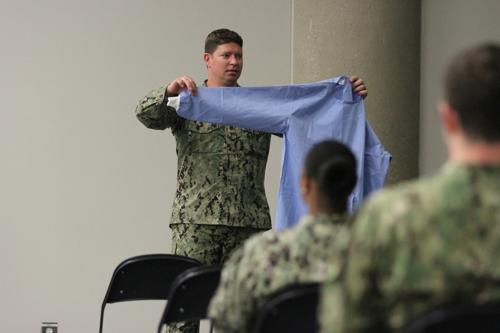 Navy Sailors apart of the Expeditionary Medical Facility get Personal Protective Equipment training.