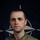 NATO BG-P EIB and ESB awardees A U.S. Army soldier is photographed in a formal portrait-style image against a NATO flag backdrop. The soldier wears OCP (Operational Camouflage Pattern) uniform with visible insignia including parachutist wings and a service ribbon. The image is part of a NATO eFP (enhanced Forward Presence) Battle Group promotional campaign.