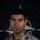 NATO BG-P Soldiers test on EIB and ESB tasks A U.S. Army soldier poses for an official portrait in front of a NATO flag backdrop. The soldier is wearing MultiCam (OCP) camouflage uniform with visible U.S. Army tape, unit patches, and qualification badges. This appears to be an official NATO Enhanced Forward Presence (eFP) Battle Group promotional portrait.