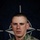 NATO BG-P Soldiers test on EIB and ESB tasks A U.S. Army soldier poses for an official portrait in front of a NATO flag backdrop. The soldier is wearing MultiCam (OCP) camouflage uniform with visible rank insignia, unit patches, and qualification badges. The image is part of a NATO eFP (enhanced Forward Presence) Battle Group public affairs campaign.