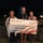 Three individuals are posing outdoors at night holding a large ceremonial check made out to the Coast Guard Foundation for $12,000.00, dated January 21, 2019. The check is from LT Duane Thomas Zitta and is designated for the Fallen Heroes Fund. The event appears to be taking place at an outdoor venue, possibly in Hawaii given the tropical setting and lei worn by the man in the center.