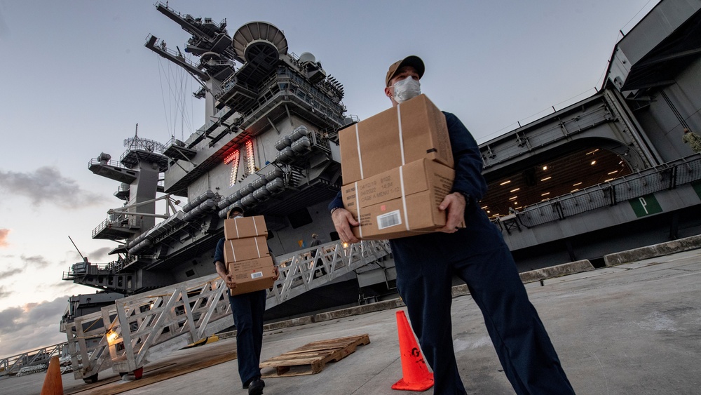 USS Theodore Roosevelt (CVN 71) move meals, ready to eat (MREs) for Sailors