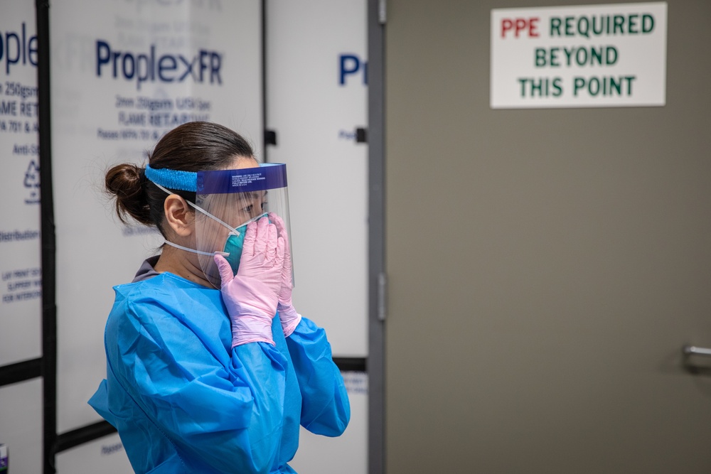 USPHS Personnel aid in the donning of PPE