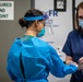 USPHS Personnel aid in the donning of PPE