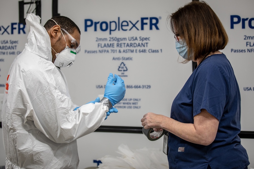 USPHS Personnel aid in the donning of PPE