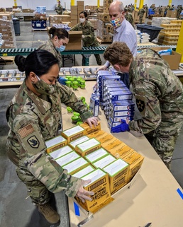 U.S. Rep. Rick Larsen helps Guardsmen build food boxes at Food Lifeline Warehouse