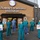 A group of approximately seven healthcare workers in teal/green scrubs and face masks are posed outside the Pickaway Correctional Institution in Ohio. Two individuals in the foreground are holding handmade signs reading 'It Starts With Us - 178 MD G'. The setting includes the institution's entrance with the Great Seal of the State of Ohio above the building name, and a security fence with razor wire visible to the right.