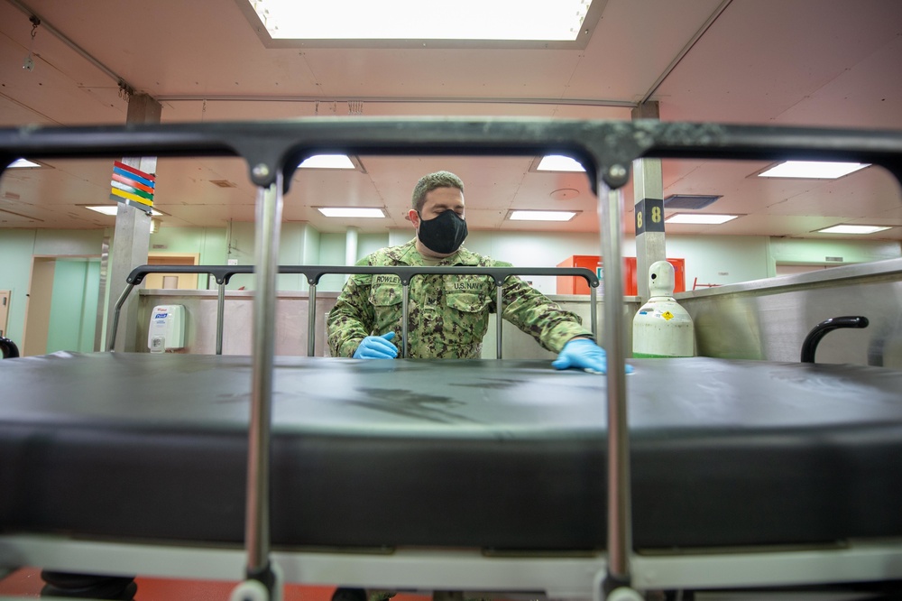 USNS Mercy Sailor Sanitizes Gurneys