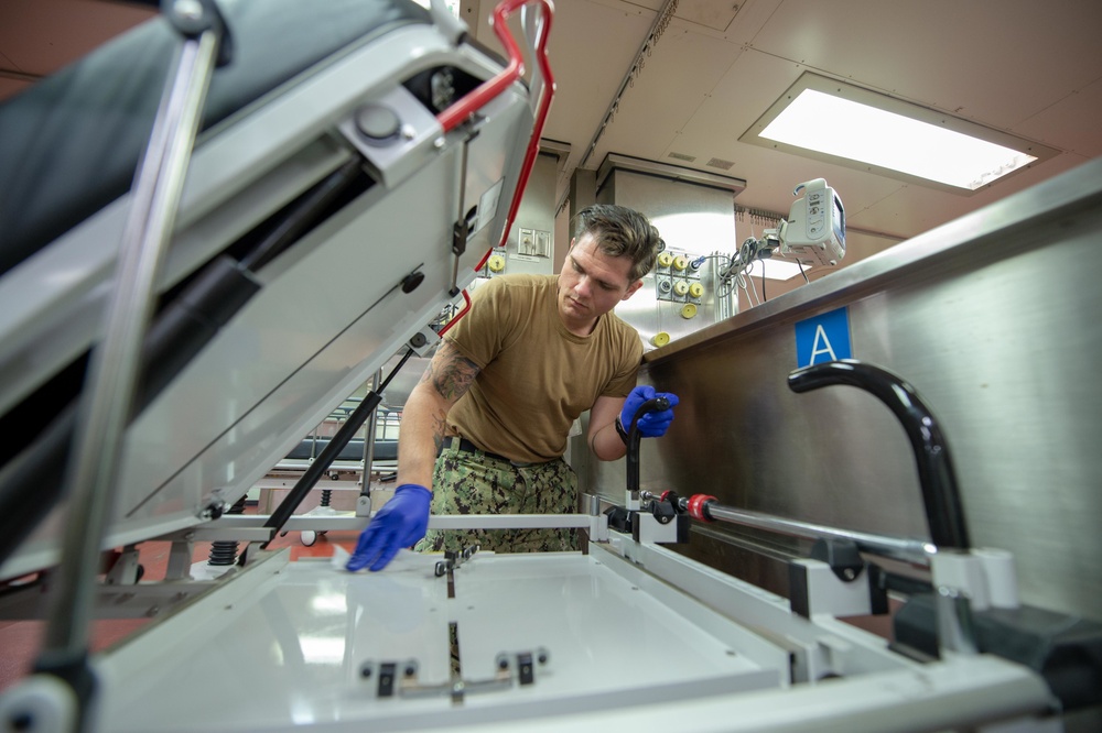 USNS Mercy Sailor Sanitizes Gurneys