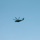 Dragon helicopter conducts Explosive Ordnance Disposal A large military helicopter is captured in flight against a clear, uniform blue sky. The helicopter appears to be a heavy-lift type with multiple main rotor blades and a tail rotor, consistent with models such as the Sikorsky CH-53. The image was taken from a low angle looking upward, with the aircraft positioned in the center-left of the frame.