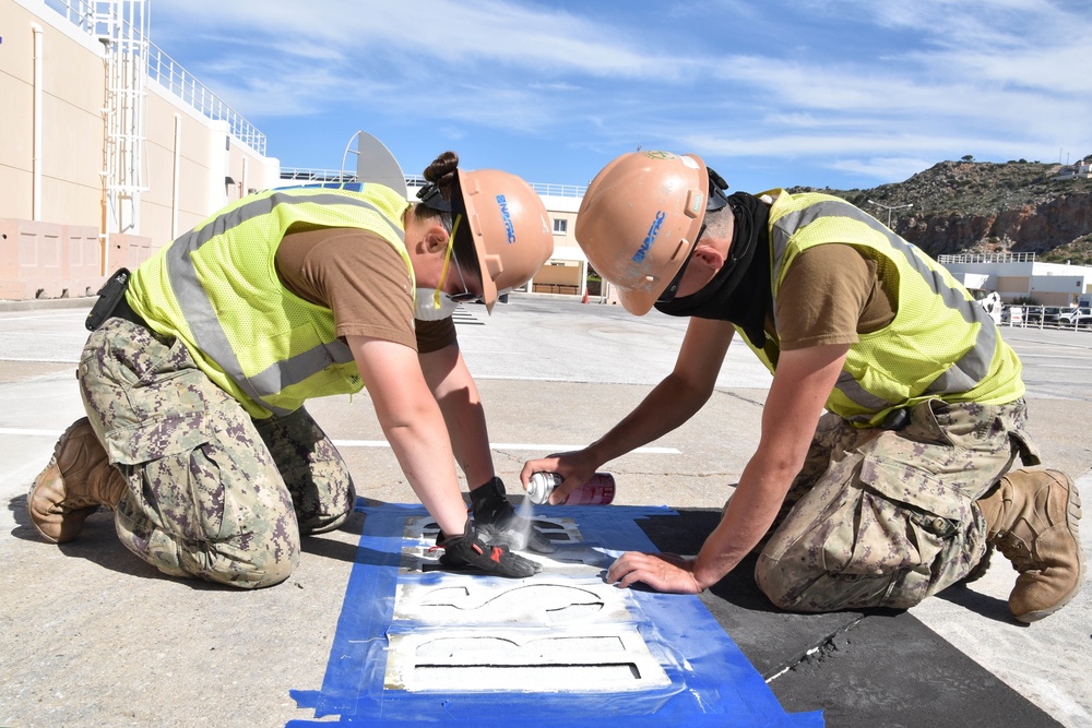 Seabees assigned to Naval Support Activity Souda Bay, Greece, Public Works Department, spray paint for a reserved parking space in the Navy Exchange parking lot