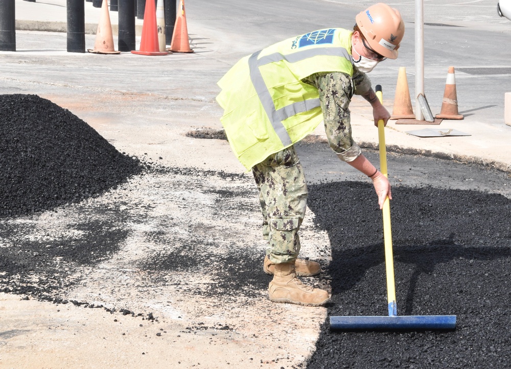 Builder Constructionman 3rd Class Meghan Plunk smooths asphalt in the Navy Exchange parking lot on NSA Souda Bay, Greece