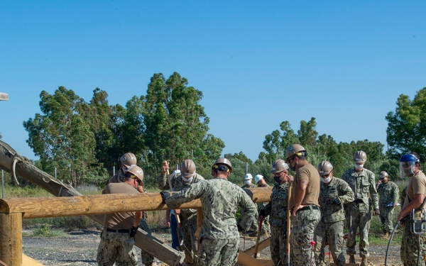 NMCB 1 Seabees fill post holes with concrete during an obstacle course construction project.