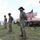 1st Battalion, 8th Cavalry Regiment Change of Command Three U.S. Army soldiers wearing distinctive black cavalry Stetson hats and face coverings stand at attention during what appears to be a formal military ceremony. An American flag on a staff is positioned beside a Bradley Fighting Vehicle in the background. The unit patch visible on the soldiers' shoulders appears to be the 1st Cavalry Division patch.