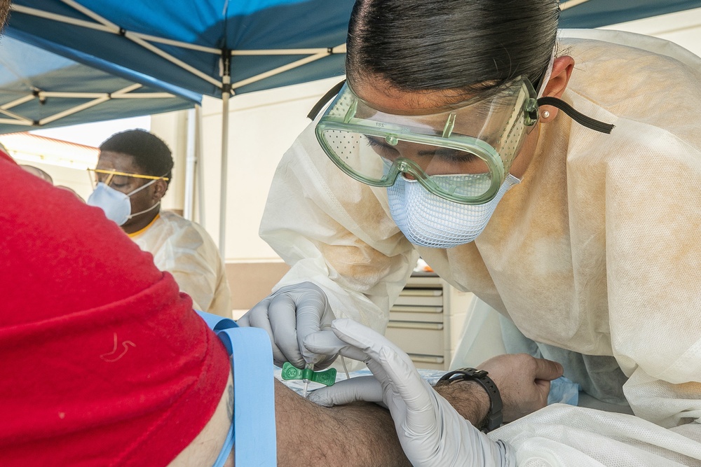 Navy Corpsmen with U.S. Naval Hospital Guam take samples from Sailors attached to USS Theodore Roosevelt for a CDC Study