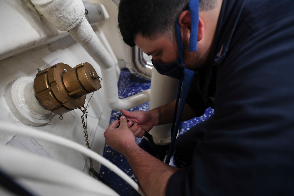 Sailor conducts maintenance on valve