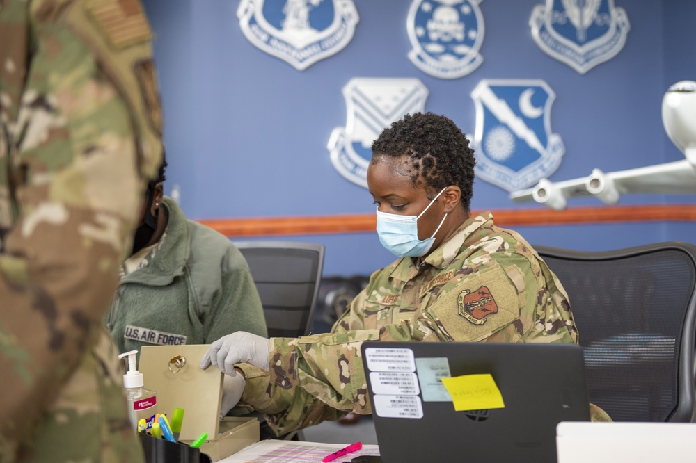 116th Medical Group personnel implement COVID-19 mitigation techniques to process Airmen during drill