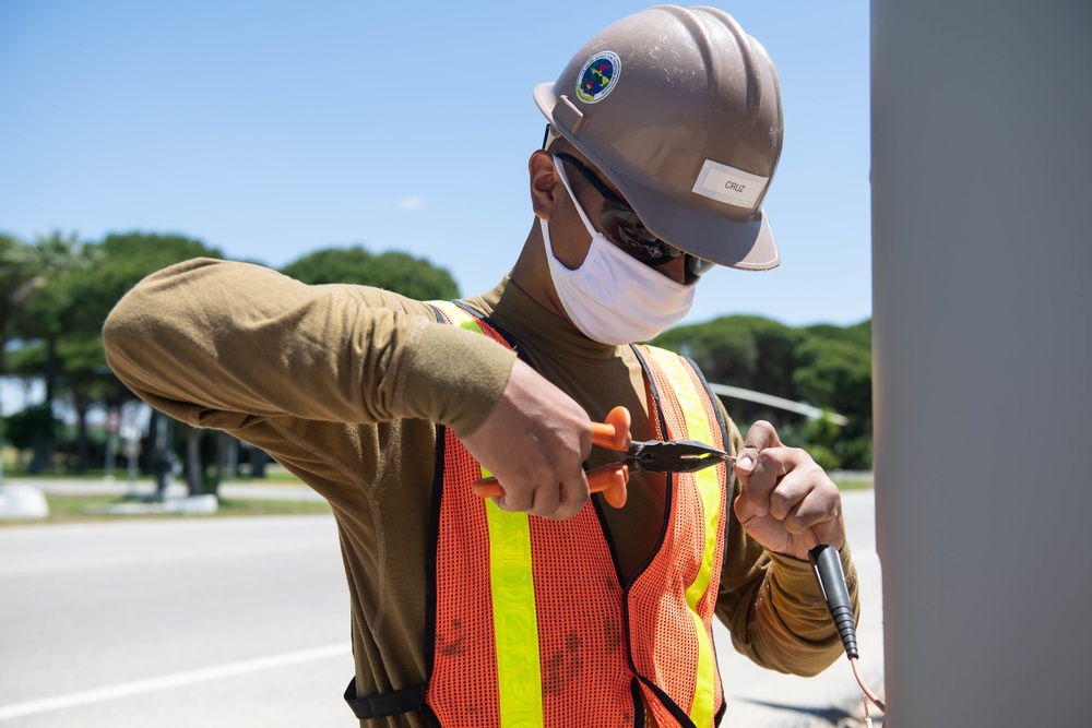 Seabees assigned to Naval Mobile Construction Battalion (NMCB) wire a pole during a street lighting construction project on aboard Naval Station Rota, Spain.