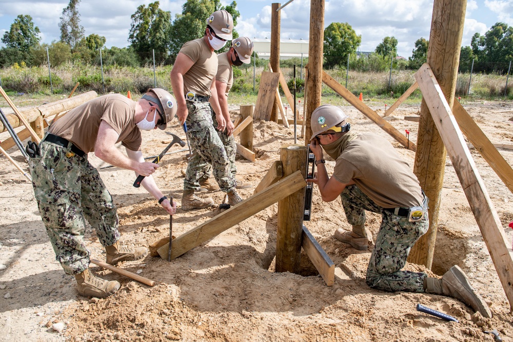 Seabees assigned to Naval Mobile Construction Battalion (NMCB) space and secure a log during an obstacle course construction project on aboard Naval Station Rota, Spain.