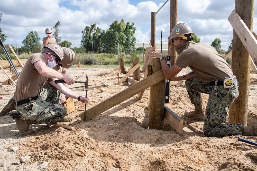 Seabees assigned to Naval Mobile Construction Battalion (NMCB) space and secure a log during an obstacle course construction project on aboard Naval Station Rota, Spain.