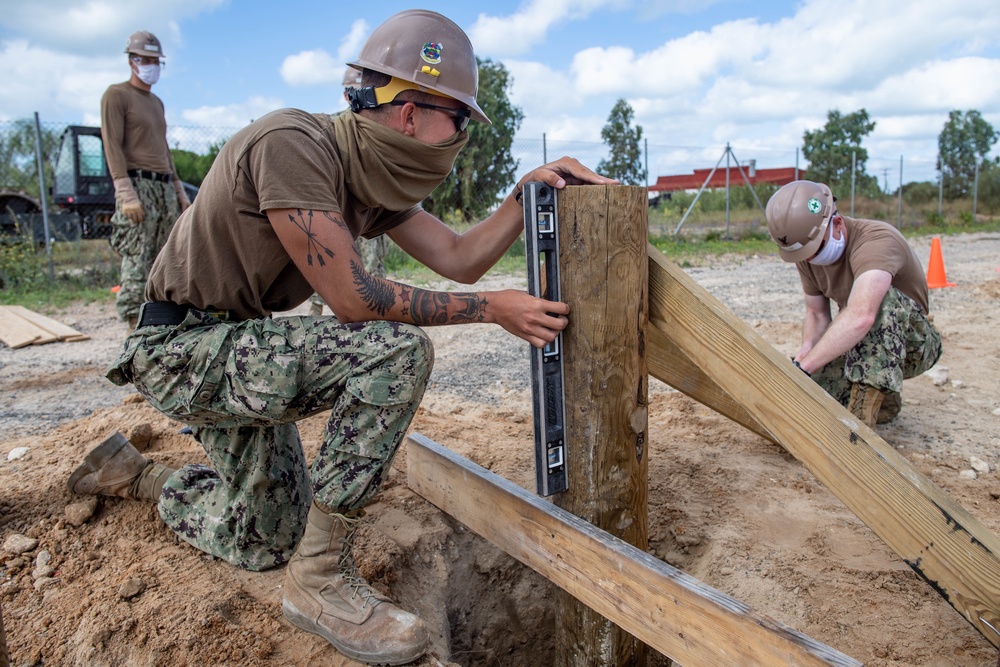 Seabees assigned to Naval Mobile Construction Battalion (NMCB) space and secure a log during an obstacle course construction project on aboard Naval Station Rota, Spain.