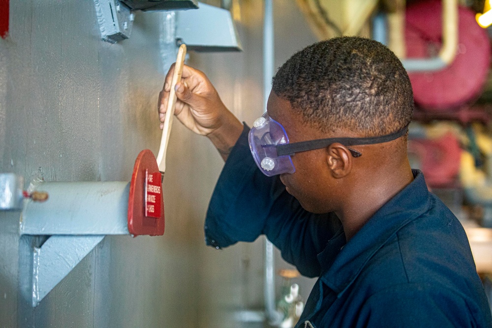 Sailors paint a bulkhead