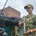 Airman Olivia Lawrence, assigned to USS Constitution, poses with a plugged and shined 40mm round from the saluting onboard Constitution