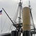 A shinned and plugged 40mm round is photographed in front of USS Constitution