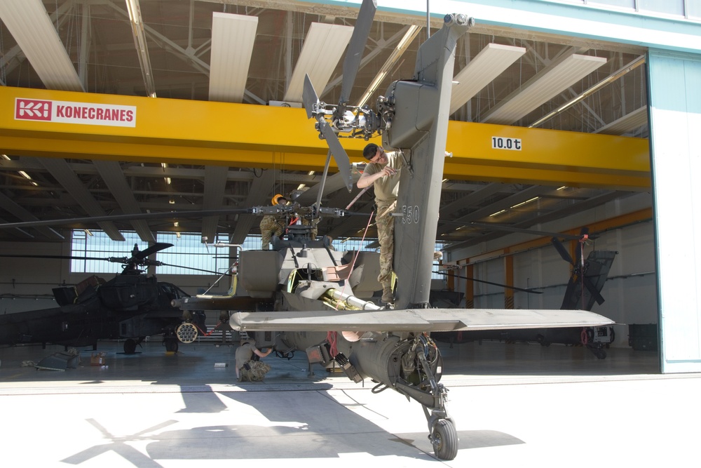 Soldiers perform maintenance on an Apache helicopter