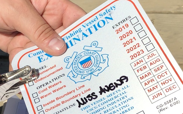 A Coast Guard marine inspector with Sector Anchorage issues a decal indicating that the vessel Miss Avena passed a commercial fishing vessel safety exam in Levelock, Alaska, June 16, 2020. Displaying this decal on the Miss Avena will assure Coast Guard law enforcement officers on the water that the vessel is in compliance with federal safety laws. U.S. Coast Guard photo by Petty Officer 1st Class Nate Littlejohn