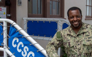 IS2 Joshua James stands in front of the entrance of Commander, Carrier Strike Group (CCSG) 15