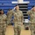 Korea’s Top Dentist Changes Command Four U.S. Army soldiers in Operational Camouflage Pattern (OCP) uniforms are rendering a salute inside what appears to be a gymnasium or indoor sports facility. Three soldiers in the foreground are prominently saluting, while a fourth soldier wearing a face mask stands in the background. This appears to be a formal military ceremony, likely a change of command or similar official event.