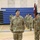 Korea's Top Dentist Changes Command A formal U.S. Army military formation is taking place inside a gymnasium or indoor sports facility. A senior officer, identifiable by rank insignia and name tape reading 'SWEET,' stands at the front center, with soldiers in OCP (Operational Camouflage Pattern) uniforms arranged in rows behind. A guidon bearer holding a dark red/maroon pennant flag stands to the officer's right.