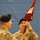 Korea's Top Dentist Changes Command Two U.S. Army soldiers in OCP (Operational Camouflage Pattern) uniforms are handling a maroon/burgundy guidon pennant during what appears to be a military ceremony. Both soldiers are wearing black berets, and one has a U.S. flag patch and a unit shoulder sleeve insignia visible on their uniform. The image is rotated 90 degrees counterclockwise.
