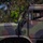 A U.S. Marine Corps military truck with camouflage paint scheme is being operated by a uniformed Marine. The vehicle is marked 'USMC-593946' on the hood and features a distinctive cab-over design. The setting appears to be an outdoor area with trees visible in the background.
