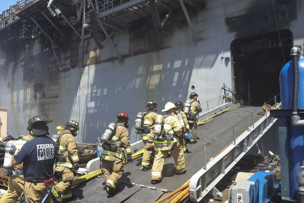 Sailors and federal San Diego firefighters fight fire aboard USS Bonhomme Richard