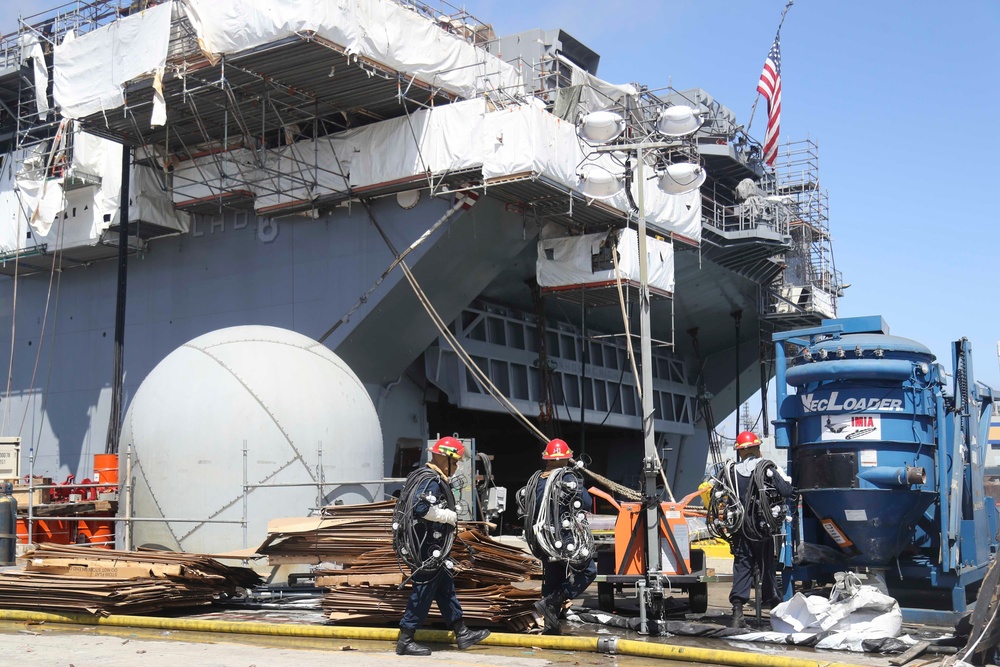 Sailors and federal San Diego firefighters fight fire aboard USS Bonhomme Richard