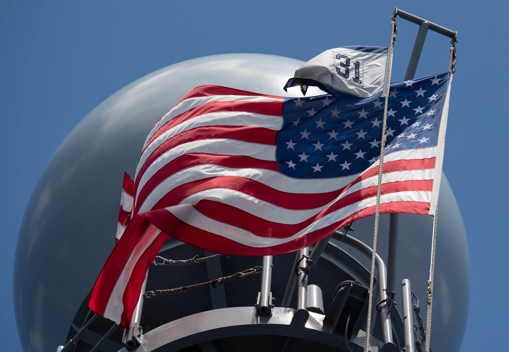 The U.S. flag flies with the Commander, Destroyer Squadron (DESRON) 31 command pennant