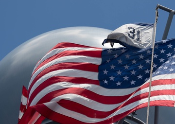 The U.S. flag flies with the Commander, Destroyer Squadron (DESRON) 31 command pennant