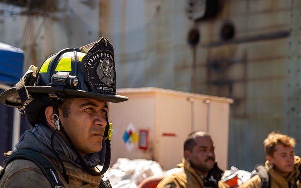Sailors and federal San Diego firefighters fight fire aboard USS Bonhomme Richard